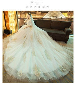 Close-up of luxury white wedding dress featuring intricate lace embroidery and a long train