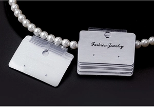 Close-up of white Fashion Jewelry display cards with a pearl necklace on black background