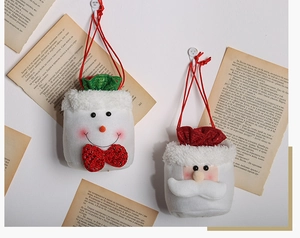 Detail of plush Christmas gift bags with snowman and Santa hanging on a vintage wall