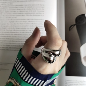 Polished silver fluid ring on model hand with open book background for lifestyle aesthetic