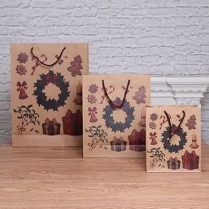 Three sizes of brown kraft Christmas gift bags with holiday patterns near a cozy fireplace