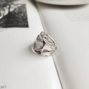 Irregular textured wide 925 sterling silver open ring on minimalist paper background