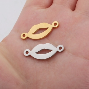 Close-up of gold and silver lip-shaped metal charms on a palm for DIY jewelry