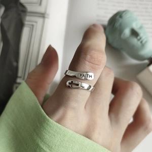 Detailed view of FAITH engraved sterling silver cross ring worn on finger in daily setting