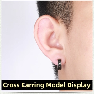 Close-up of black punk cross clip-on earring in stainless steel worn on the earlobe