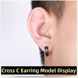 Close-up of black punk clip-on earring featuring a white cross pattern on a male model