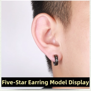 Close-up of black punk clip-on earring with silver star pattern worn by a male model