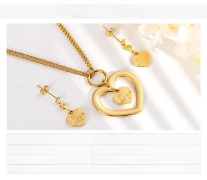 Close-up of gold stainless steel hollow heart pendant and earrings with Love engraving
