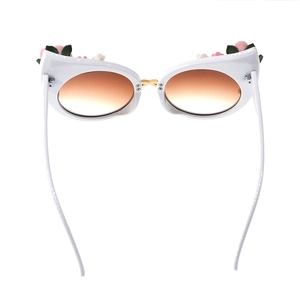 Detailed view of white cat-eye sunglasses with 3D floral accents and gradient lenses