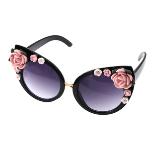 Cat eye sunglasses with floral accents and purple gradient lenses on a white background