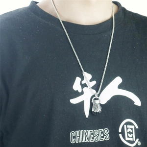 Primer plano de un collar con colgante de puño plateado usado por un modelo hombre