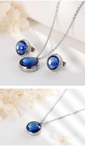 Close-up of silver-toned necklace and earrings set with round blue cubic zirconia and halo