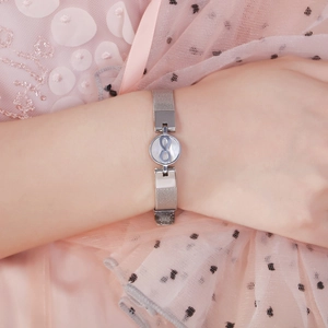 Silver mesh bracelet with infinity symbol charm worn on a wrist over a pink dress