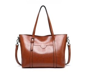Détail d'un sac cabas en cuir marron avec texture brillante et bretelles réglables