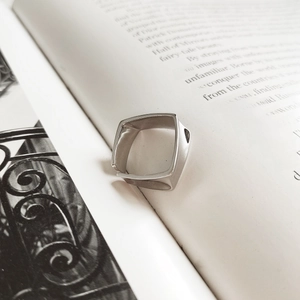 Macro view of square geometric silver ring resting on a minimalist photography book