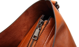 Détail du cuir marron texturé et de la fermeture éclair métallique sur un sac fourre-tout