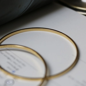 Macro shot of two slim 18K gold plated titanium steel bangles with polished mirror finish