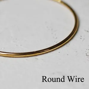 Macro detail of polished 18K gold-plated titanium steel round wire minimalist bracelet