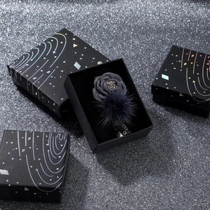 Close-up of elegant star-patterned jewelry gift boxes and fabric flower brooches