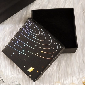Macro view of square black jewelry box with holographic galaxy design and black velvet interior