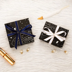 Black starry jewelry gift boxes with ribbons on white faux fur background