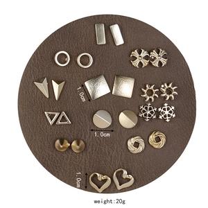 Detailed view of 12 pairs of golden geometric stud earrings on brown leather pad