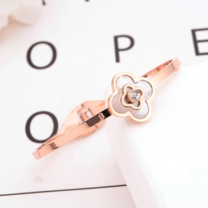 Rose gold four-leaf clover bracelet with white shell inlay and zircon on marble surface