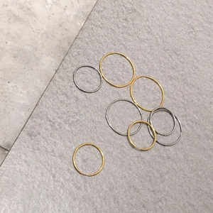 Minimalist geometric gold and silver titanium hoop earrings set on stone surface