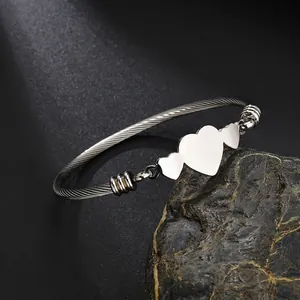Détail du bracelet en acier inoxydable argenté avec trois breloques en forme de cœur