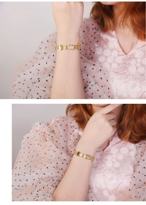 Détail d'un bracelet en maille dorée avec cœur MAMA et breloque fille sur un mannequin