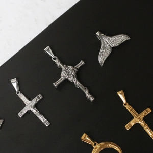 Detailed close-up of 18K gold and silver steel cross, whale tail, and moon pendants