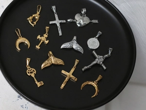 Macro shot of gold and silver 18K plated stainless steel charms on a black display plate