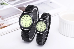 Detail of luminous black couple watches with stretch metal bands and Arabic numerals