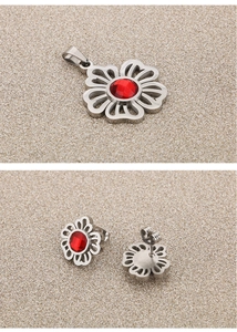 Detailed macro of hollow flower jewelry set with red gemstones on sand texture