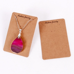 Macro shot of a teardrop agate pendant necklace displayed on a brown kraft paper card