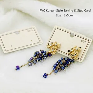 Detail of floral grape-shaped drop earrings with gradient beads on a white PVC display card