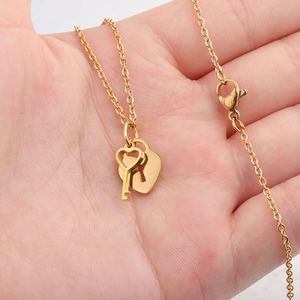 Gold heart lock and key pendant necklace in stainless steel held in palm for size