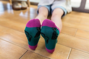 Detail shot of mid-calf cotton socks with green and pink patchwork and black butterfly print