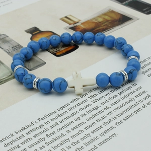 Macro detail of turquoise beaded bracelet with white cross and silver spacers