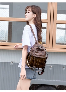 Close-up of brown vintage wax leather backpack on model showing strap and zipper details