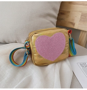 Détail du sac coeur doré à paillettes roses avec bandoulière arc-en-ciel réglable