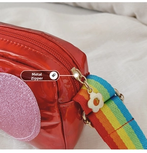 Détail du sac en cuir verni rouge avec zip fleur et bandoulière arc-en-ciel