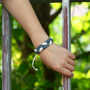 Handmade woven cotton hemp bracelet in grey-blue and cream tones on a person's wrist