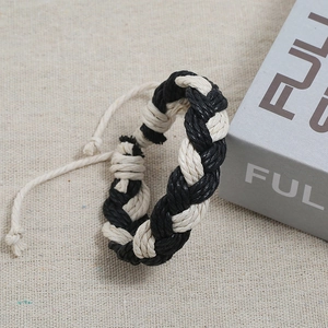 Handmade woven couple bracelet in black and white pattern on beige linen background