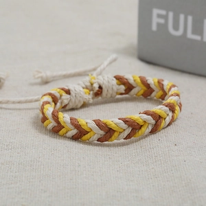 Close-up of adjustable brown and yellow braided hemp bracelet on linen texture