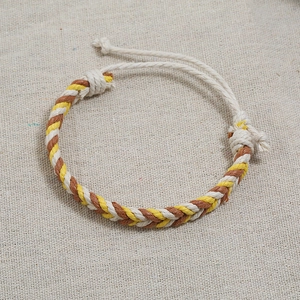 Detail of hand-woven cotton cord bracelet in white yellow and brown with adjustable knot