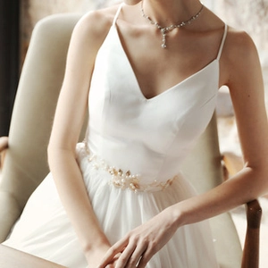Close-up of elegant gold flower and pearl embellishments on a white bridal wedding dress