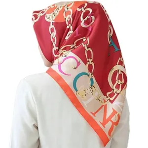 Detail of burgundy bawal hijab scarf showing gold chain print and vibrant artistic pattern