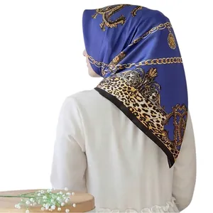 Detail of royal blue silk scarf with gold chain and leopard print in a head wrap style