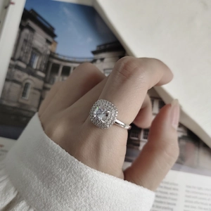 Macro shot of 925 silver halo ring with square-cut cubic zirconia on model's finger